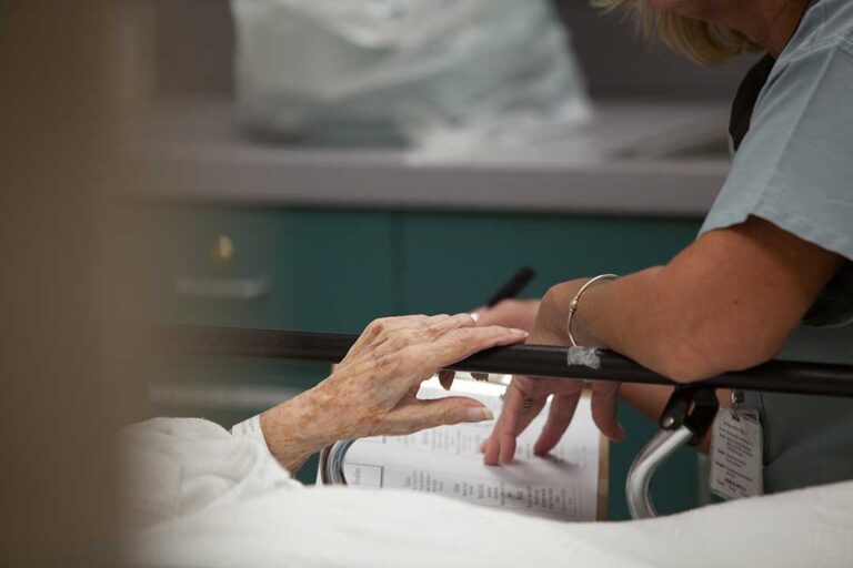 Older adult and family member review assisted living apartment features with a staff guide.