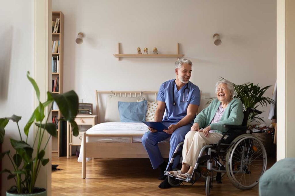 Older adult reviews a monthly care budget with a family member at a kitchen table beside assisted living paperwork.