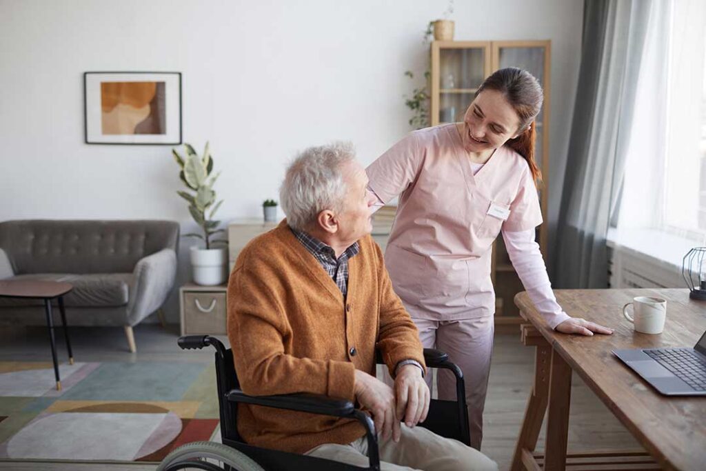 Older adult and family member reviewing Medicare papers at a kitchen table beside a pill organizer.